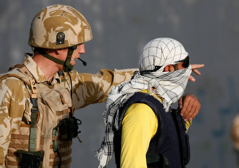 A man wearing British military uniform speaks to an Afghani man wearing sunglasses and a headscarf. Close colleagues: a British soldier with an Afghani translator after a suicide attack on a convoy of Western troops in Kabul, 2007. REUTERS/Desmond Boylan